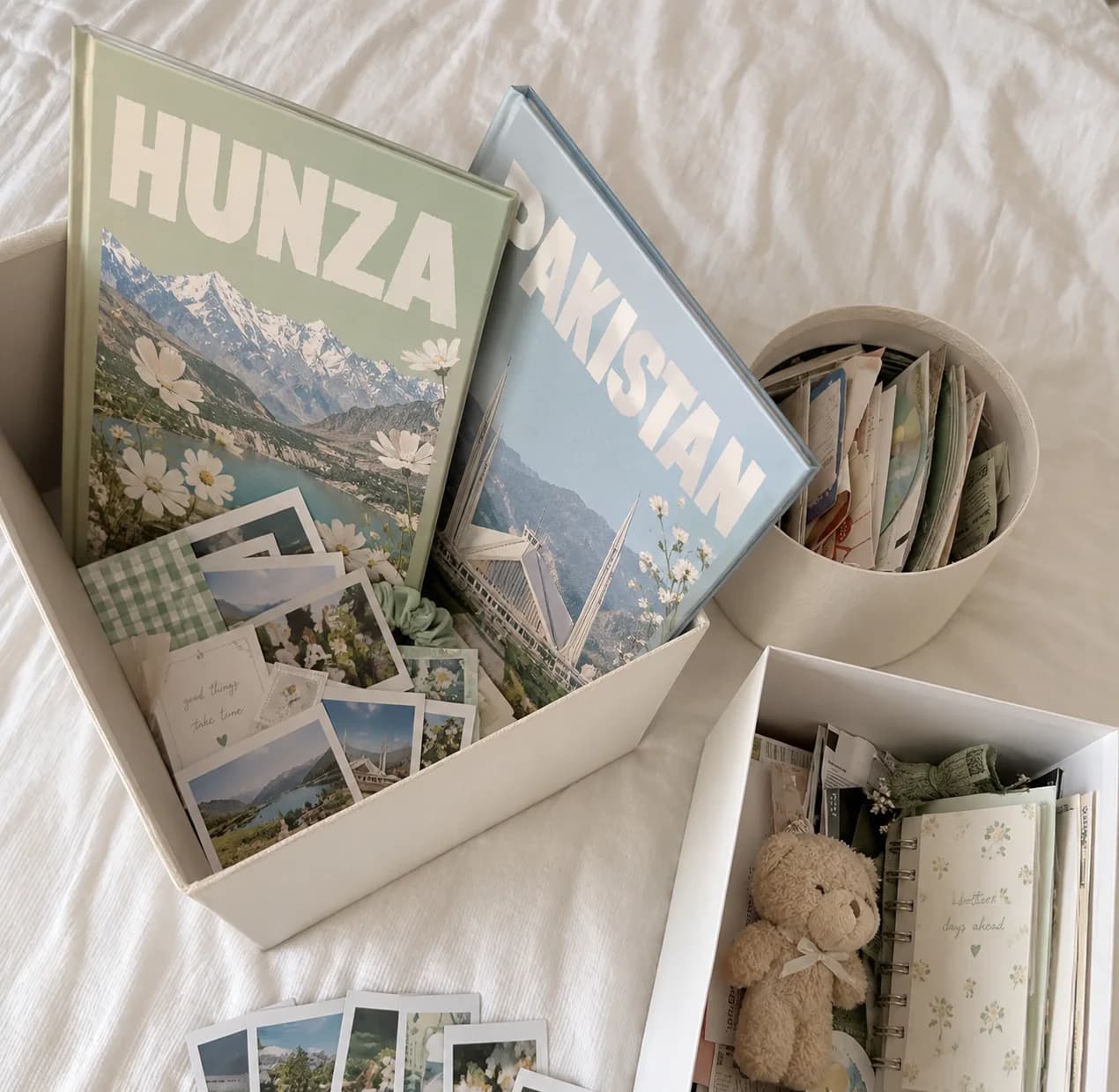 Two Mimfoto photobooks, Hunza and Pakistan, in an open box with prints, a teddy and a notebook beside them